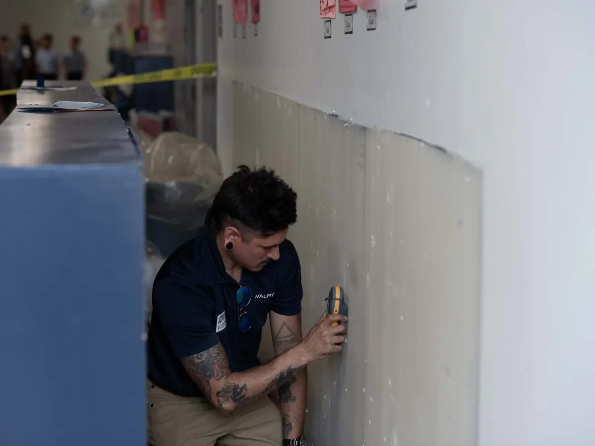 Cavalry technician checking a flood-cut wall for moisture behind a cabinet